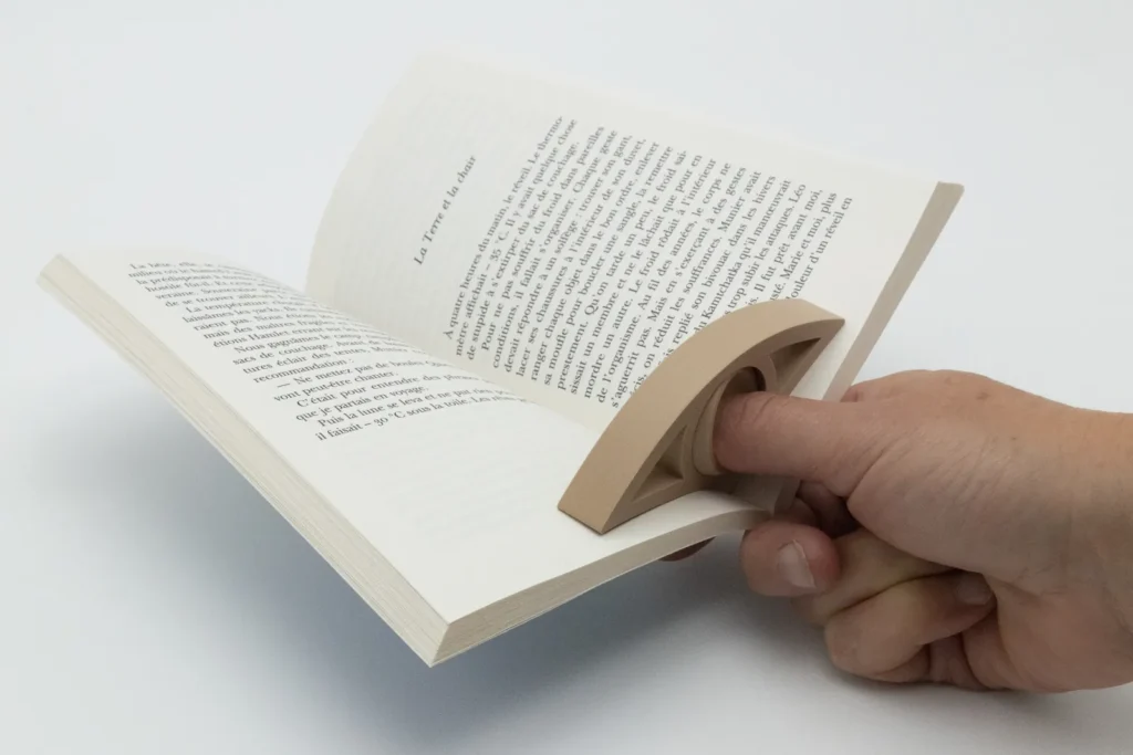 Tient-page glissé sur le pouce qui garde un livre ouvert d’une seule main